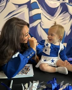 a woman sitting next to a baby on top of a table