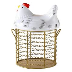 a white chicken sitting on top of a wire basket next to a metal stand with gold legs