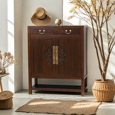 a wooden cabinet sitting next to a tree in a living room with wicker baskets on the floor