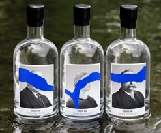 four bottles with blue images on them are lined up next to each other in the water