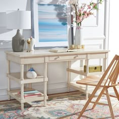 a white desk topped with a vase filled with flowers next to a chair and lamp