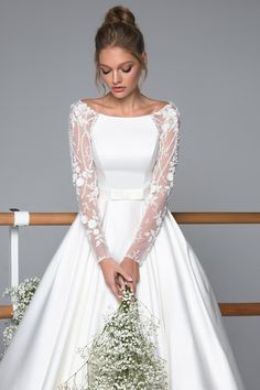 a woman in a white wedding dress holding flowers