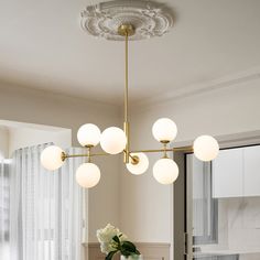 a chandelier hanging over a dining room table with white flowers in vases