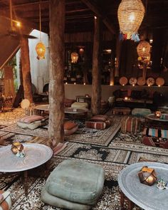 a room filled with lots of tables and stools next to tall wooden poles in the ceiling