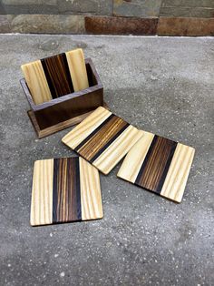 three wooden coasters sitting on the ground next to a box with wood strips in it