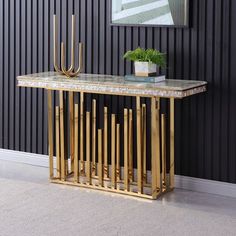 a gold console table in front of a wall with black vertical striped walls and a painting on the wall