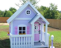 a pink and white doll house with flowers on the front door, porch and fence