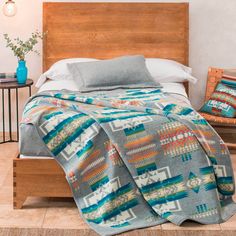 a bed with a blanket on top of it next to a wooden headboard and night stand