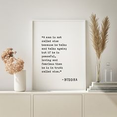 there is a vase with flowers on top of a shelf next to a framed quote