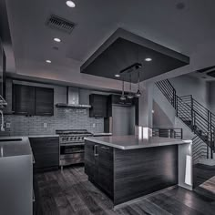 an empty kitchen with wooden floors and stainless steel appliances on the counter top, along with stairs leading up to the second floor