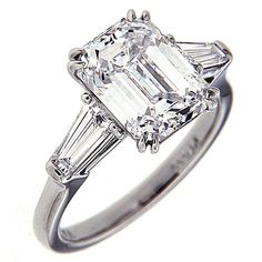 an emerald cut diamond ring with three baguets on the band and side stones