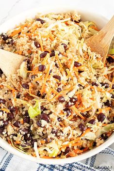 a white bowl filled with rice, beans and broccoli next to a wooden spoon