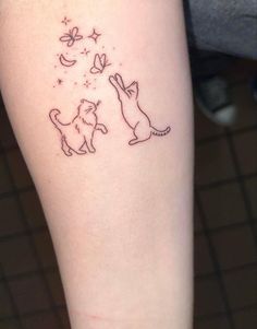 a small tattoo on the leg of a woman with two cats and stars in the sky