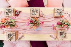 the table is decorated with pink flowers and wooden boxes for gifts on it, along with other decorative items