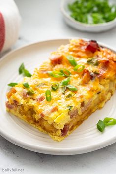 a slice of quiche on a plate with green onions and garnishes