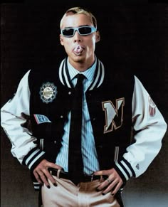 a man wearing sunglasses and a jacket with his hands on his hips, making a funny face