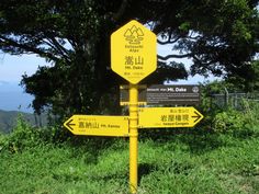 a yellow sign sitting on the side of a lush green hillside