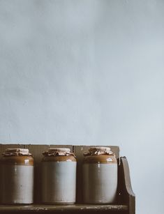 three jars sitting on top of a wooden shelf