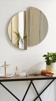 a mirror on the wall above a table with a plant and other items next to it