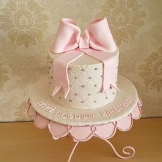 a pink and white cake with a large bow on it's top sitting on a table