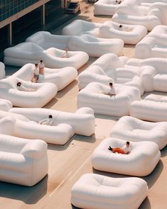 people are sitting on giant white couches outside