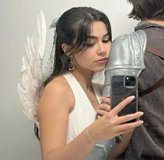 a woman is taking a selfie with an angel wings on her head while holding a cell phone