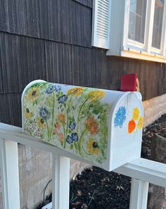 a painted mailbox sitting on the side of a house