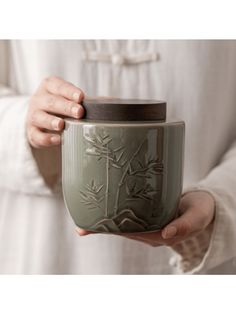 a person holding a cup in their hands with the lid up to show it's design