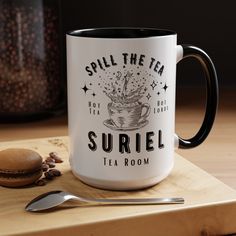 a coffee mug sitting on top of a cutting board next to a spoon and cookie