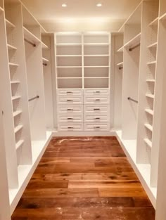 an empty walk - in closet with white shelves and wooden flooring, along with shelving units