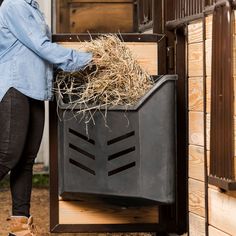 a woman standing next to a horse trailer with hay in it's bins