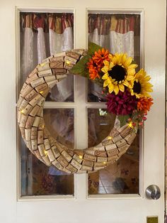 a wine cork wreath with sunflowers and other flowers on the front door sill