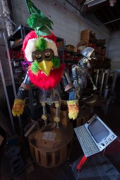 a bird made out of plastic sitting on top of a table next to a laptop computer