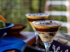 two glasses filled with dessert sitting on top of a table