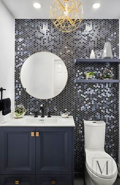 a white toilet sitting next to a bathroom sink under a golden chandelier in a bathroom