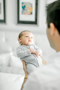 a man holding a baby in his arms while he looks at the other person's face