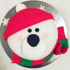 a frosted cake decorated with a polar bear wearing a red hat and green scarf