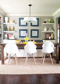 a dining room table with chairs and pictures on the wall in the backround