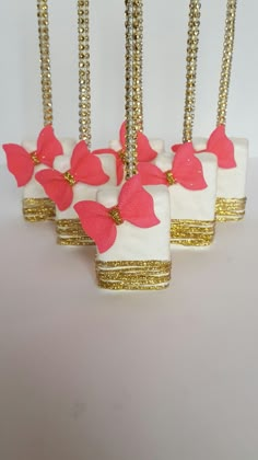 four white vases with pink flowers and gold trimmings are hanging from chains