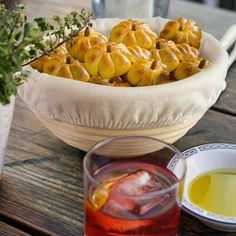 a bowl full of food sitting on top of a wooden table next to a drink