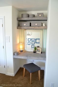 a desk with a mirror, stool and pictures on the wall in front of it