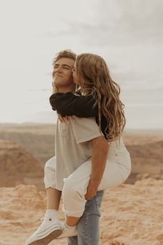 a man and woman hug in the desert, while one holds his head to her chest