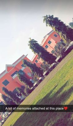 a red building sitting on the side of a lush green hillside next to a park