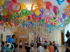 a room filled with lots of balloons and streamers hanging from the ceiling above it