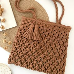 a brown crocheted purse sitting on top of a table next to a plate