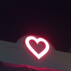 a heart shaped neon sign on the side of a building