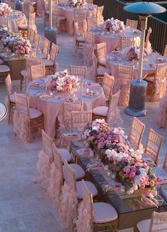 tables and chairs are set up for an outdoor wedding reception with pink flowers on them