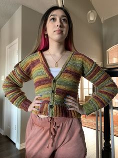 a woman with pink hair wearing a multicolored cardigan