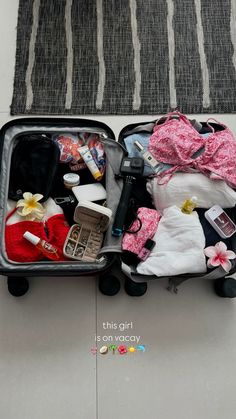 an open suitcase filled with clothes and other items on top of a floor next to a rug