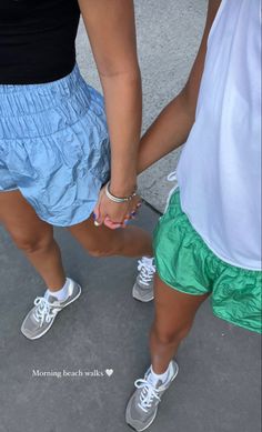 two people holding hands and walking down the street with their feet on each other's hips